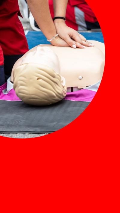 A person with both hands on a CPR doll on the floor