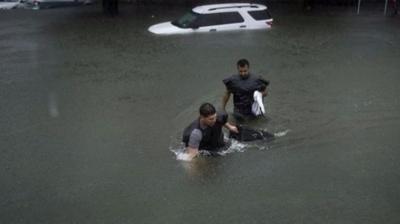 People walk through flooded street