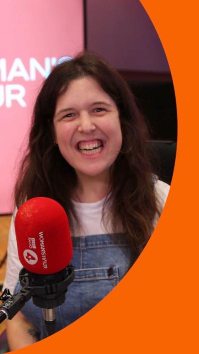 Actor and comedian Rosie Jones smiles in the Woman's Hour studio - she has long dark hair and wears denim dungarees