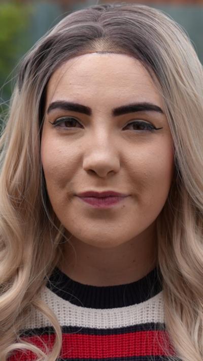 A woman with blonde hair wearing a white and blue top