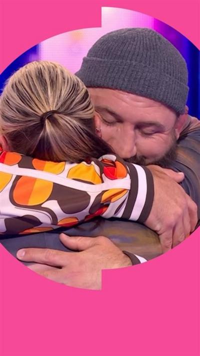 Joe Marler embraces contestant Hannah in the Wheel studio. He wears a grey beanie hat and a patterned tracksuit
