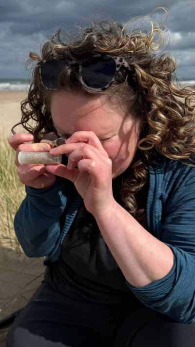 A woman with brown curly hair surveying a small specimen.