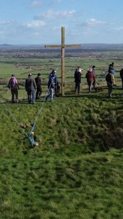 A group of people stood at the base of a crucifix cross on Brent Knoll in Somerset.