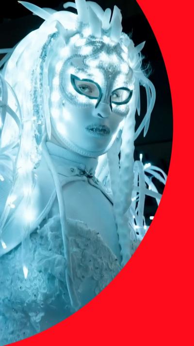Performer in glowing white LED costume and sequined mask