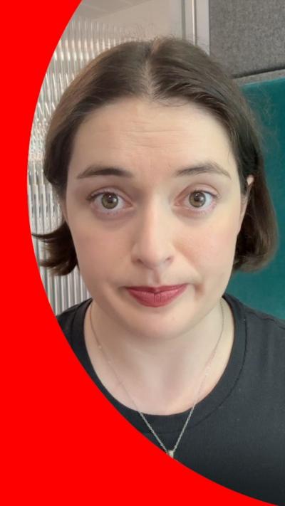 A woman with cropped brown hair looks into the camera.