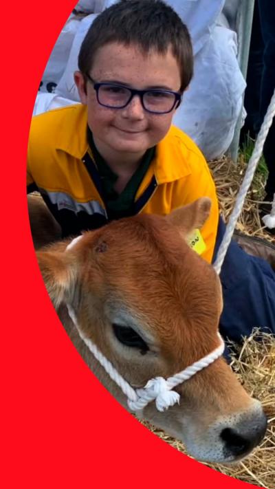 Smiling boy with glasses posing with a young calf