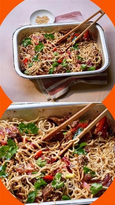 A metal tray containing crispy chilli beef and noodles. A pair of tongs rests on the side
