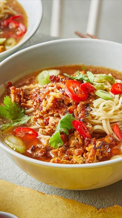 A white bowl with tofu peanut ramen in. 