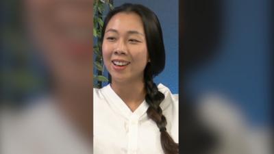 Journalist Mengchen Zhang speaks during the podcast. She has long black hair in a pigtail and wears a white top