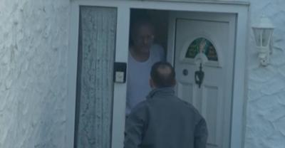 Nathan Gill standing looking out from his open door, Wyre Davies, a BBC reporter is at the door.