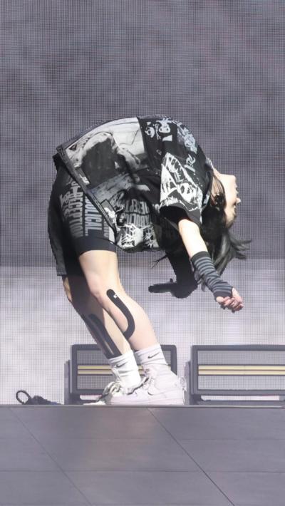 Billie Eilish leans over backwards wearing black and white bike pants and baggy thshirt as she performs at Glastonbury 2022 