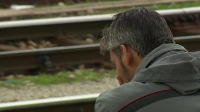 Migrant man sat next to empty railway lines