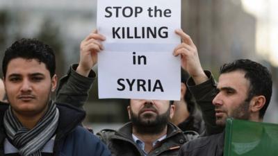 A man holds a placard during a demonstration outside of the United Nations (UN) Offices in Geneva on the opening day of Syrian peace talks