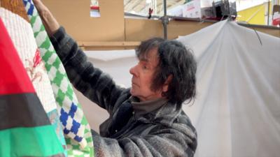 Man with grey jacket and black hair working on a market stall