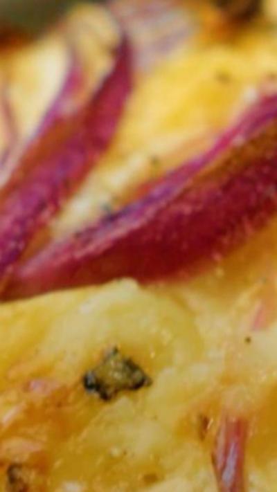 A close-up image of a cheddar and red onion tartlet.