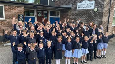 Children cheering outside Queen Elizabeth II School