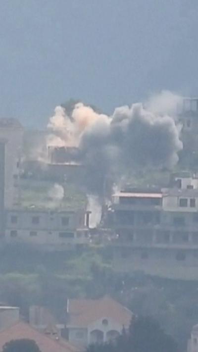 Plume of white and grey smoke rising in the middle of buildings