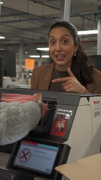 A woman with dark hair pulled away from her face points at exams being loaded into a machine