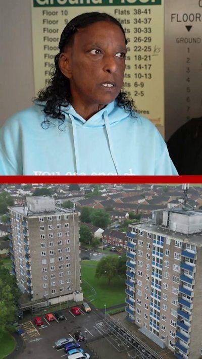 A woman in a blue hoody stands in front of a sign listing the floors in a block of flats, the bottom half of the split screen image shows two tower blocks.
