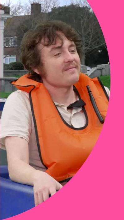 Sam Campbell has brown hair and is wearing an orange life-jacket
