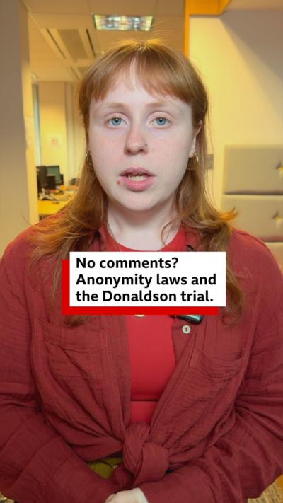 a woman in a red shirt looks at the camera 
