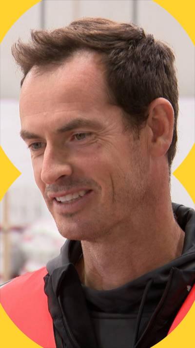 Sir Andy Murray looks to the left of the camera and smiles.