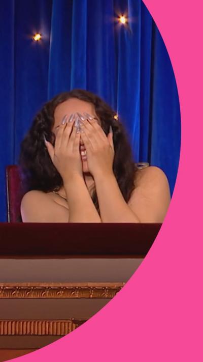 Jade is covering her face with her hands while sat in a theatre box. She has long black hair