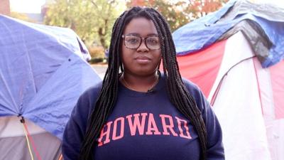 Howard student stands in front of tents