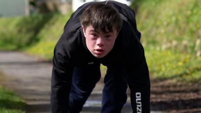 Lloyd with his hand on the track ready to start running