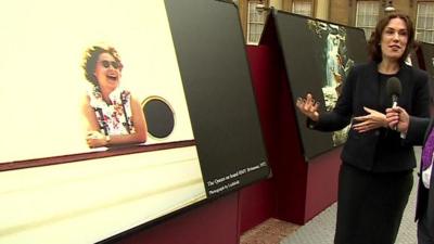 Head of Photographs at the Royal Collection Trust, Sophie Gordon, standing in front of a photograph showing the Queen laughing