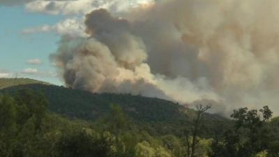 A plume of smoke billows over a hill in southern France after wildfires blaze in the area.