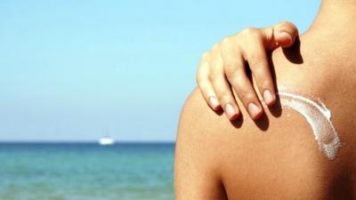 Boy applying sun cream to his back