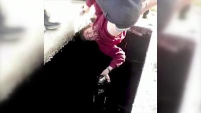 Boy being lifted out of oil well upside-down