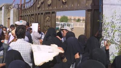 People wait for food vouchers in Sana'a.