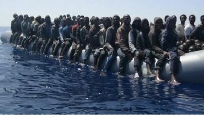 Migrants sit on edges of dinghy