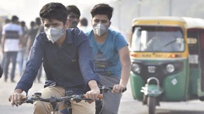 Men wearing masks ride bicycles in Delhi