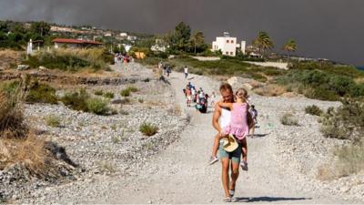 A man carries a child away from smoke