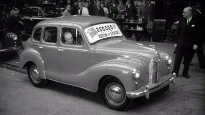 Black and white image of a new British Austin car coming off the production line, ready for being exported to Australia in 1950