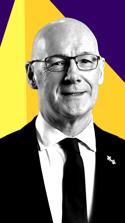 Scottish National Party leader John Swinney smiles at the camera. He is wearing a suit and tie.