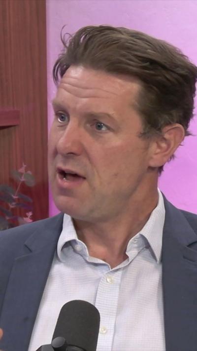 A man, Fraser Nelson, in a BBC studio - he is wearing a grey suit jacket with an unbuttoned white shirt