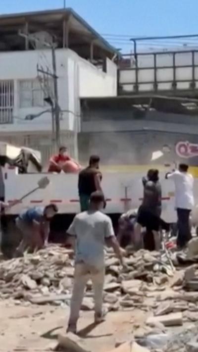 Various men are helping clear debris after earthquake.