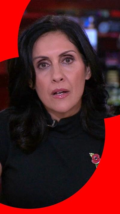 A woman with dark brown hair wearing a black high neck top