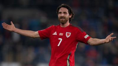 Wales midfielder Joe Allen smiles with arms outstretched 