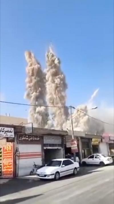 Plume of dust and smoke after air strike behind row of shops