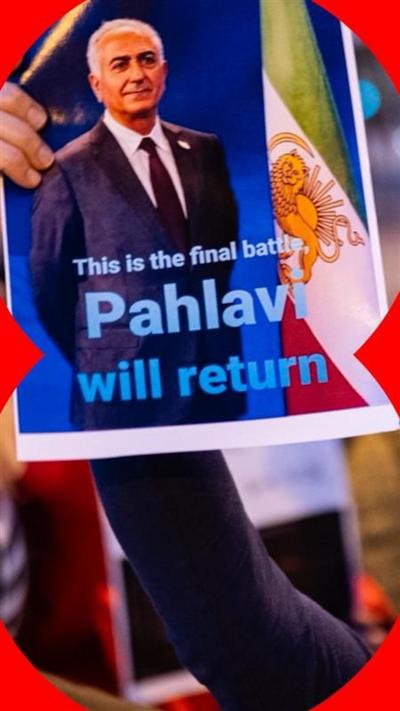 Man holds aloft a poster with and image of Reza Pahlavi and the words 'Pahlavi will return'