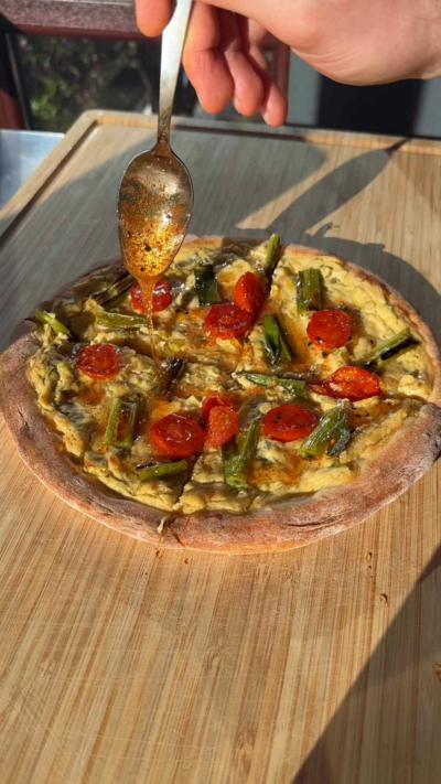A flatbread topped with hummus and spring onion on a wooden chopping board
