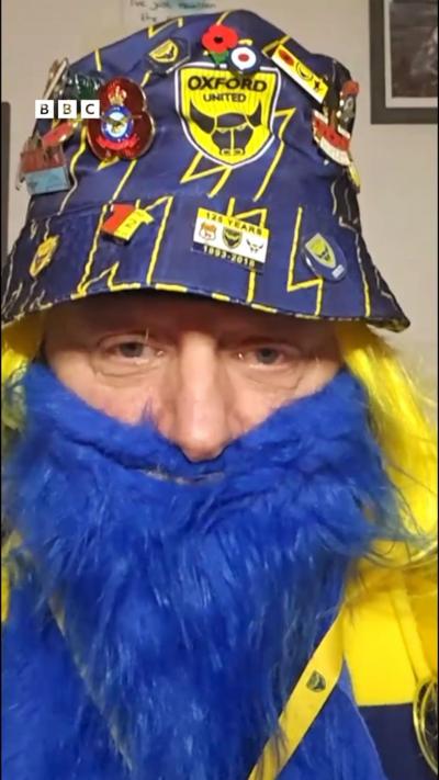 A man in a blue hat, wearing a blue beard.