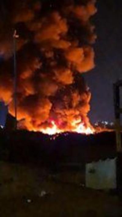 A large plume of smoke being released from a fire. The photograph is taken at night and the fire is blazing. 