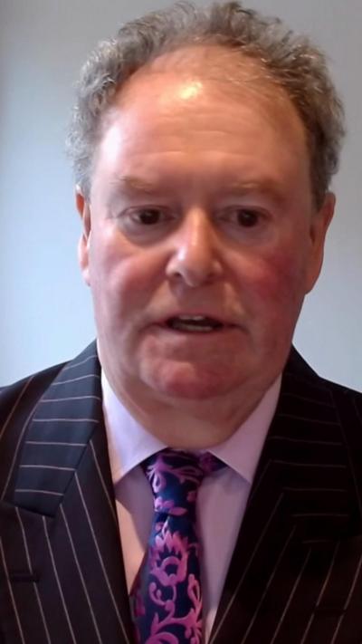 Man with grey hair dressed in suit and tie