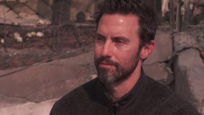 Milo Ventimiglia in front of rubble of homes